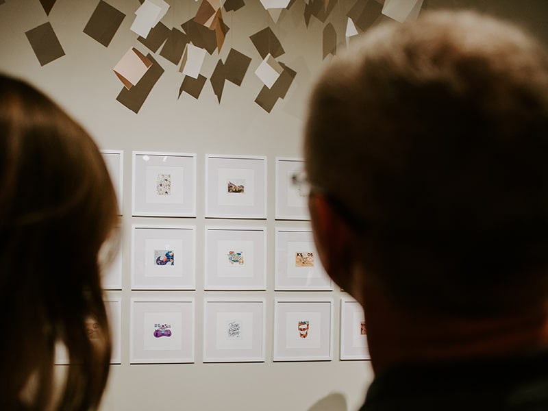 Two people looking at a gallery wall with artwork