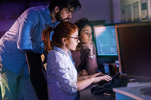 Group of people working on programming around a computer