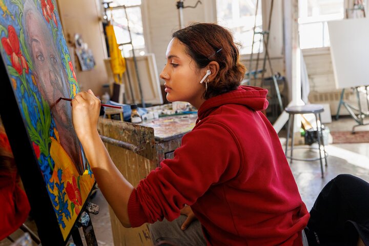 A painter works on details of a portrait.