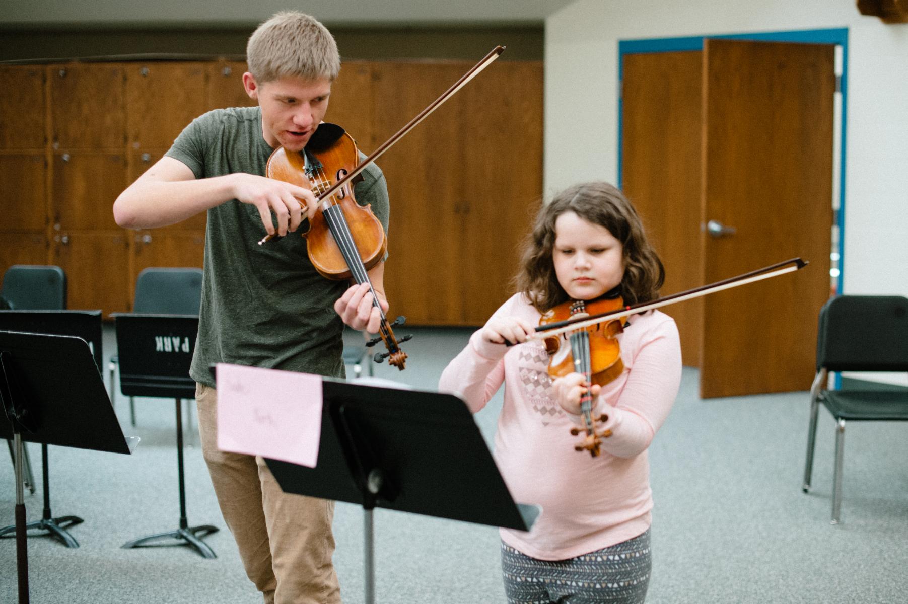 Undergraduate Student teacher plays a duet with a string project