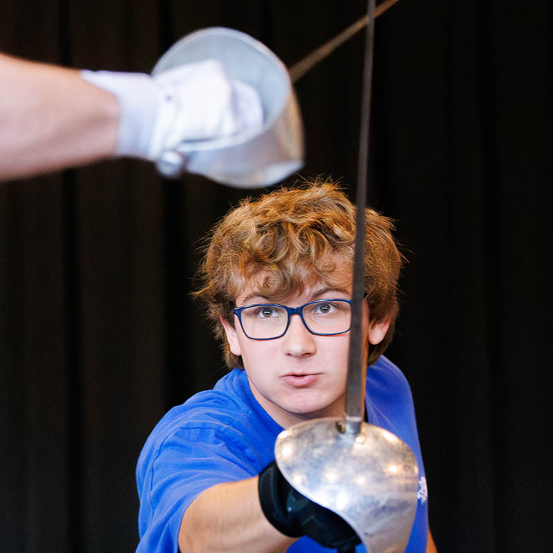 Fencing match with close-up of swords and gloves.