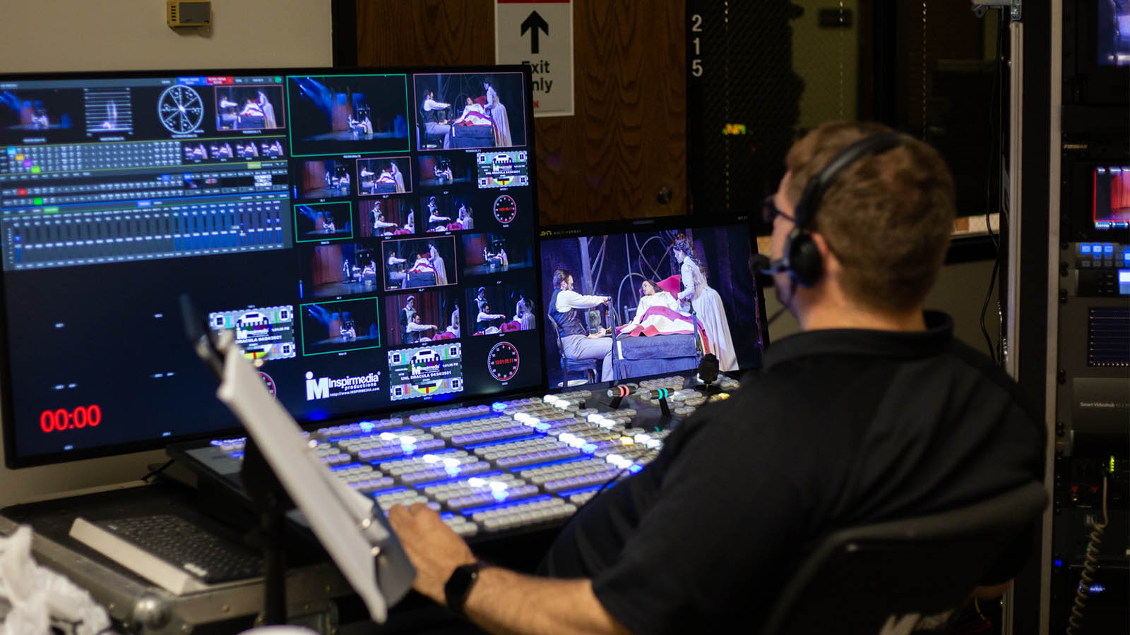 Technician operates a multi-screen control panel displaying live video feeds and production elements.