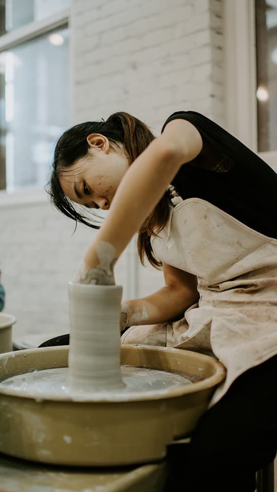 A ceramics student builds a vessel on the pottery wheel.