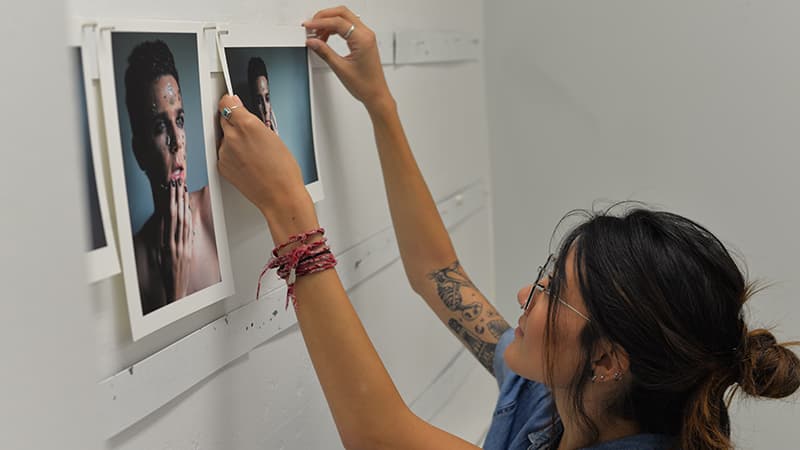 A student hangs up her photos in preparation for a student critique.