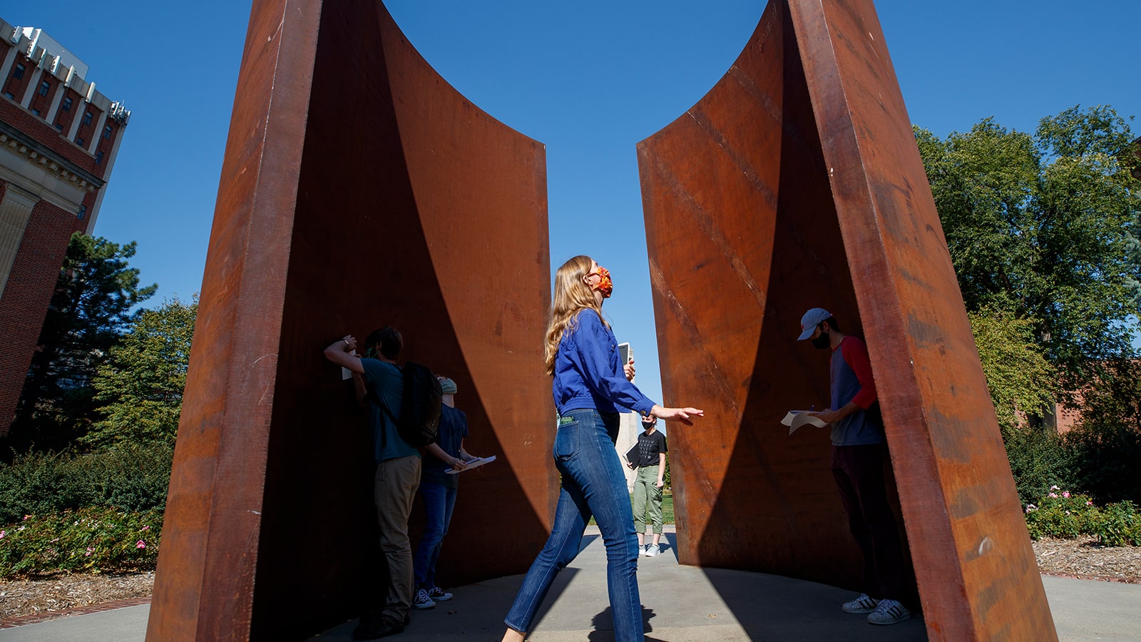 instructor and students near an outdoor sculpture