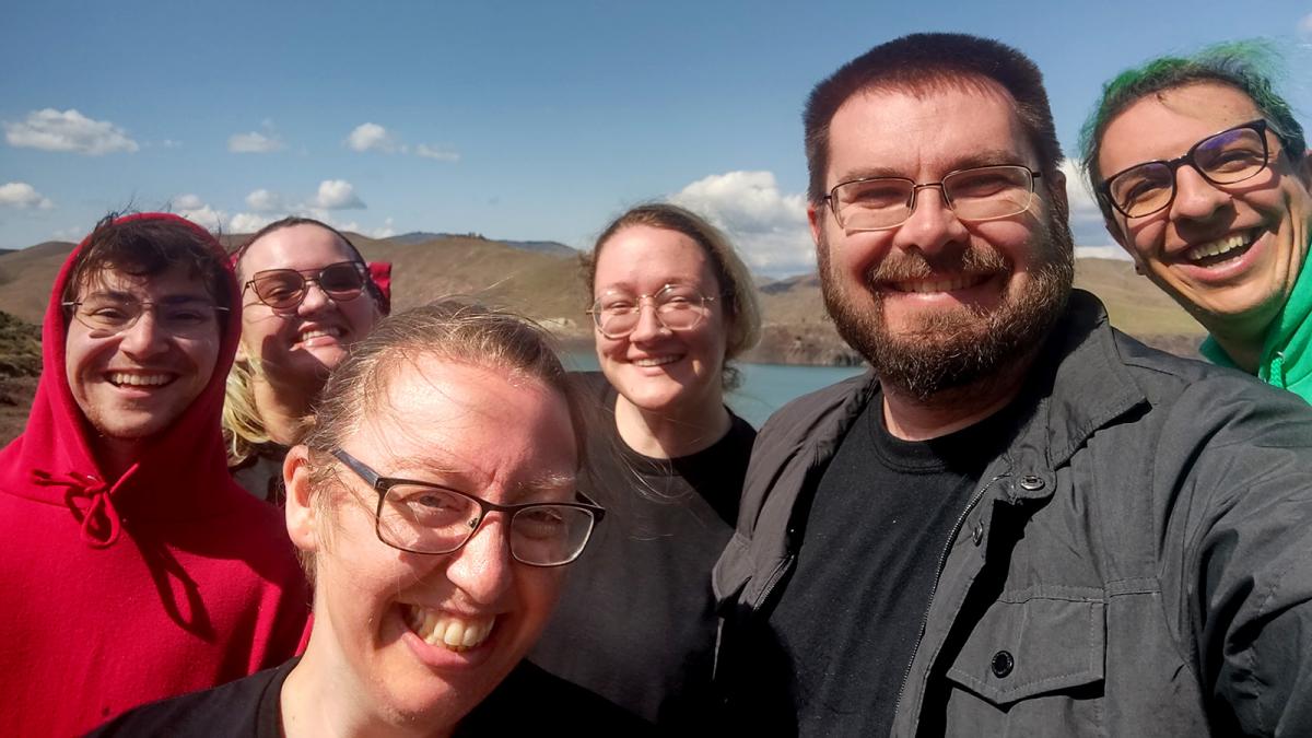 Five Carson School students pose with Assistant Professor of Practice Bryce Allen for a picture in front of a outdoor landscape in Boise, Idaho.