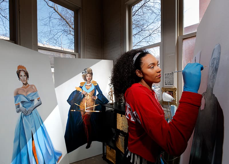 A student paints full body portraits.