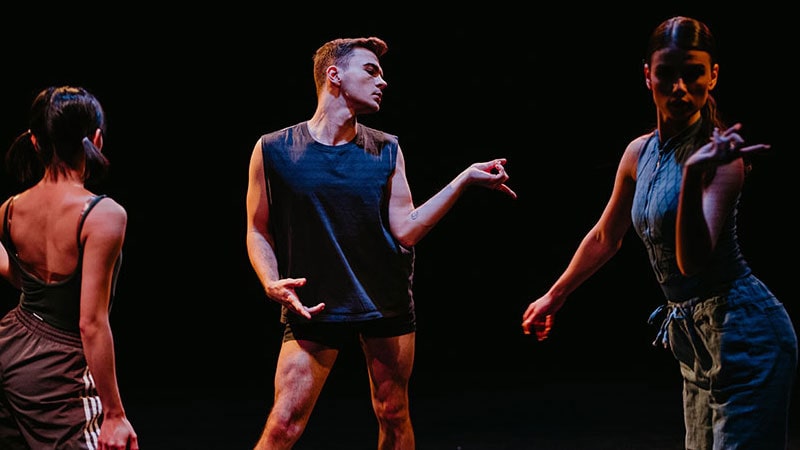 three modern dancers in dramatic lighting