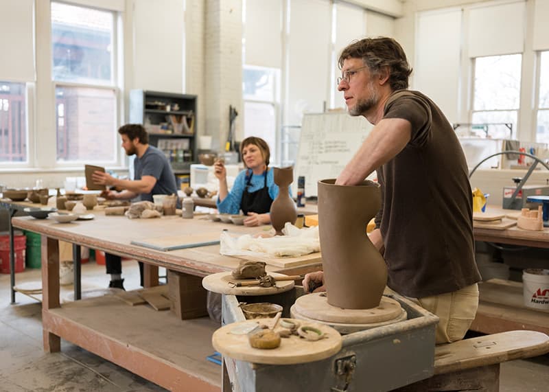 A guest artist works on a ceramics project during a class demonstration.