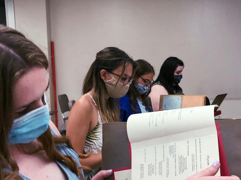 Four SAI members sitting at a long table in a classroom looking at yearbooks from the Kappa Chapter's collection.