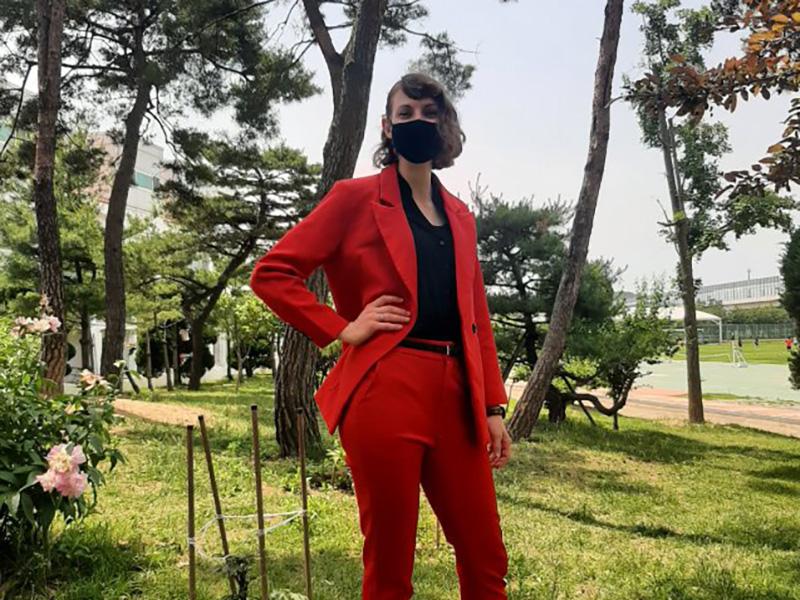 Karissa Van Liew posing for a photo in front of trees in a scarlet colored suit in Inchon, South Korea.