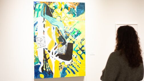 a woman stands in front of a large painting