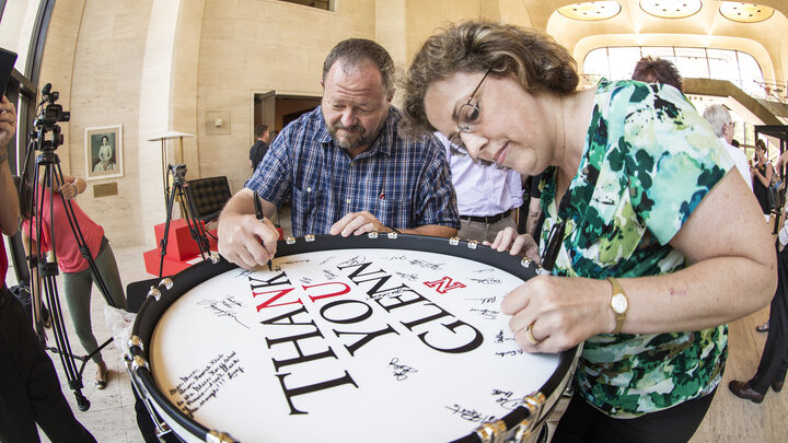 John Bailey and Gretchen Foley sign a bass drum during the Aug. 20 celebration of an $8 million gift by Glenn Korff. The drum was a gift for Korff.