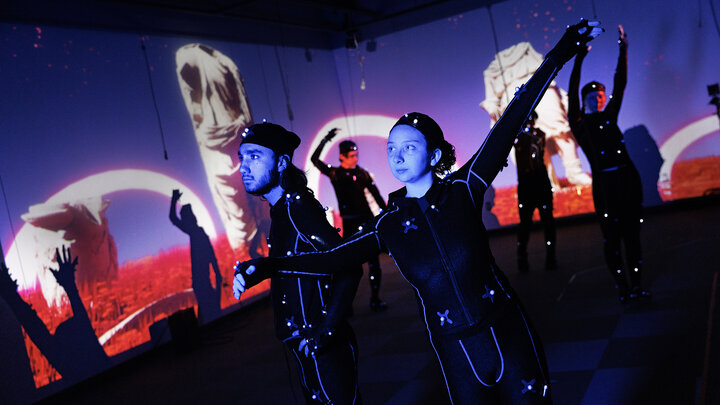 Isaiah Griffith (left) and Marley Hewitt, second-year students in the Johnny Carson Center for Emerging Media Arts, pose in motion-capture suits that will help transform them into animated characters on the surrounding screen.