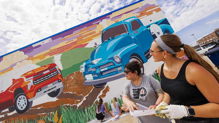 Sandra Williams, center, and Maddie Vanderbur, a senior in graphic design and the mural's designer, look over a printout of the mural. 