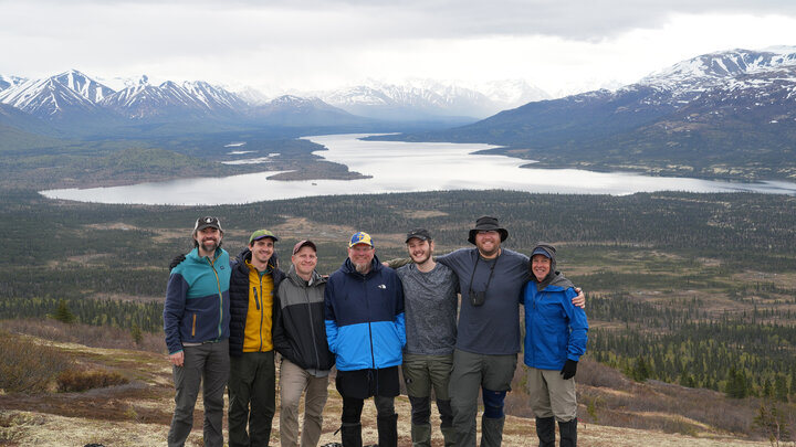 L-R: Composers Jason Carl Rosenberg, Robert Alexander, Kory Reeder, Paul Rudy, Ryan McQuay Meredith and Trevor Frost with Stephan Lias in Lake Clark National Park in 2023. Their works will be performed by the Wind Ensemble on Oct. 9. Courtesy photo.