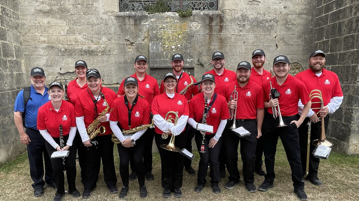 Tony Falcone (left, in blue shirt) with the 13 current and former members of the Cornhusker Marching Band who performed as part of the 80th anniversary D-Day ceremonies in France this summer. Courtesy photo.