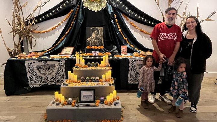 Angelica Tapia and Victor Hernández Chávez stand in front of Día de los Muertos installation.