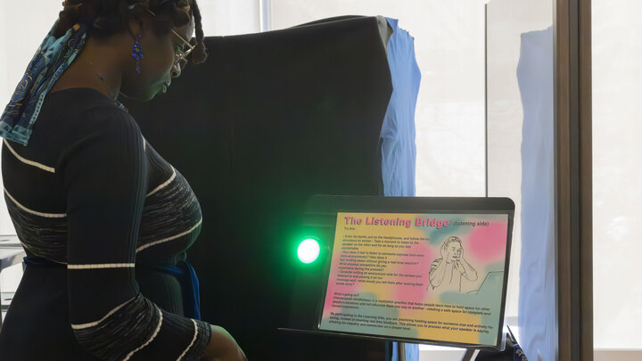 Kiewit Luminarium Program Coordinator Alajia McKizia reads the instructions for “The Listening Bridge,” before entering the booth at a demonstration of science exhibit prototypes created by students in Assistant Professor of Emerging Media Arts Jesse Fleming’s Innovation Studio course this fall. Photo by Grace Worden.