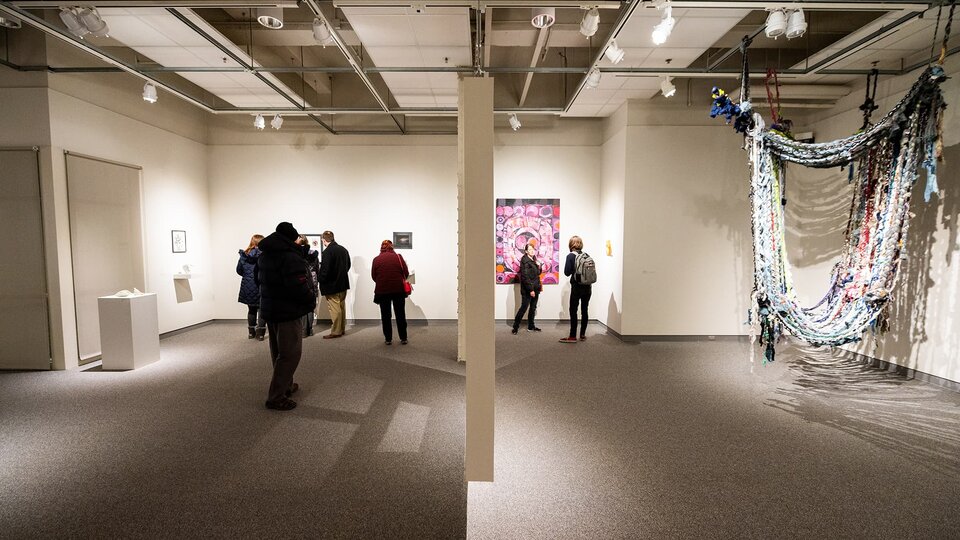 Patrons gather in the gallery to look at student work.