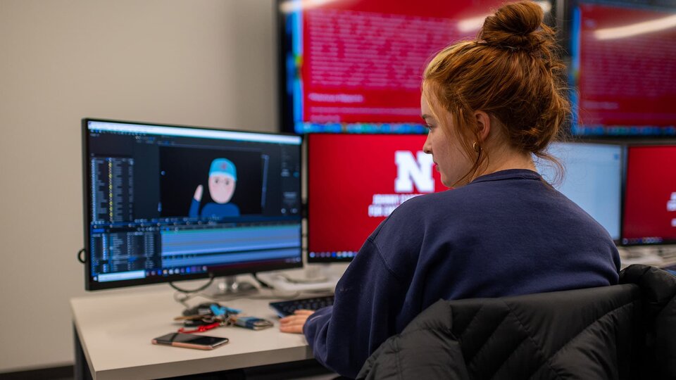 A student sits in front of computer working on an animation project.