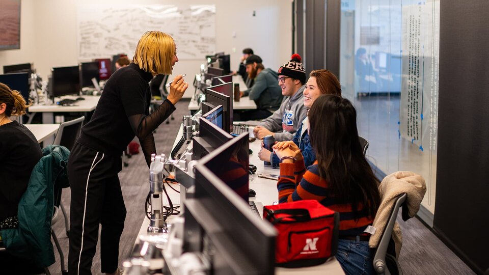 People engage in a lively talk in a well appointed computer lab.
