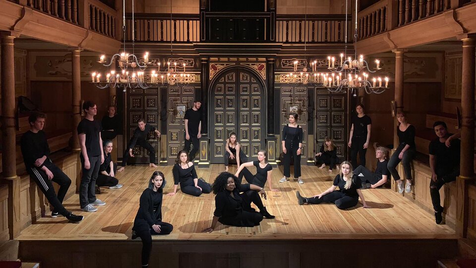 A group of students pose on stage at the Globe Theatre in London.