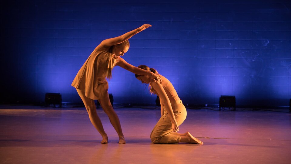 Two dancers pose dramatically on stage.