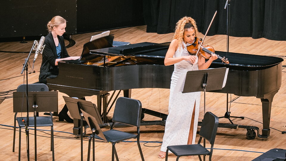 A pianist accompanies a violinist on stage.