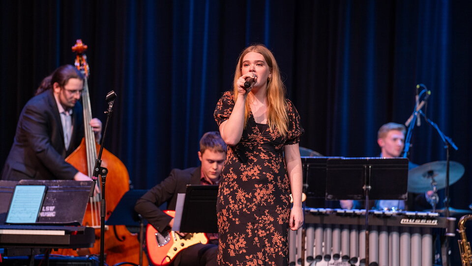 A singer performs with a band on stage.