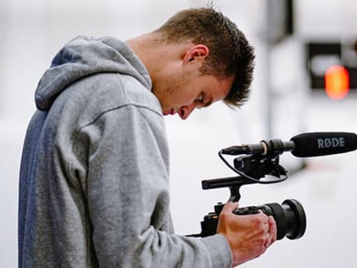 Sam Rice looks through the viewfinder of a video camera.