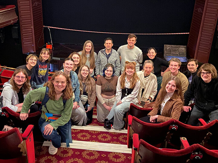 Students and professors sit in the balcony of a beautiful theatre.