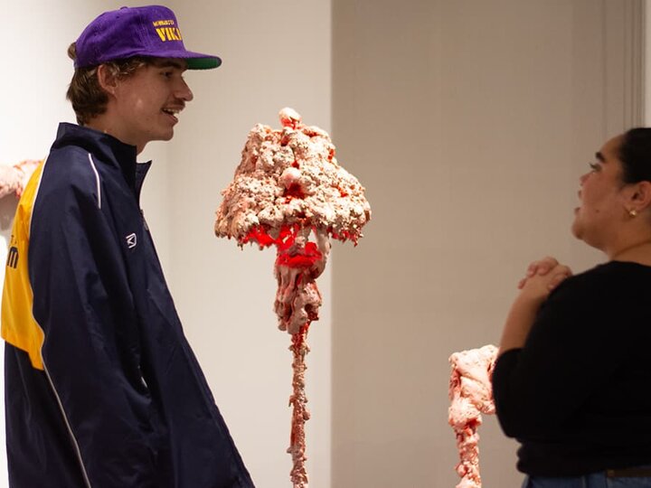 two people standing talking in front of several fleshy organic looking pieces.