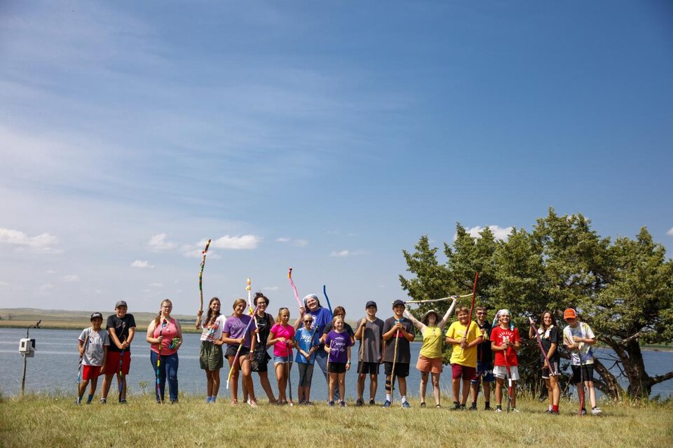 Students in a line on the shore of a pond.