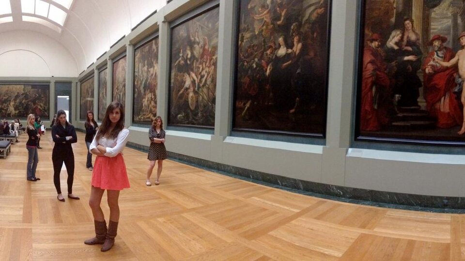 A woman stands looking at artworks in a museum.
