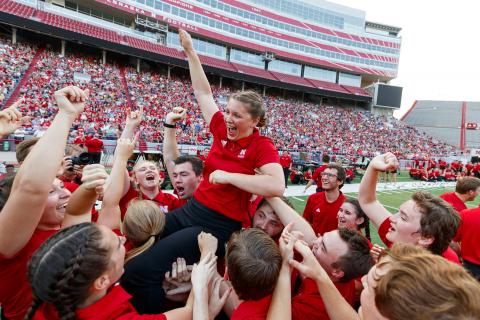 Sophia Kallas of Green Bay, Wisconsin, is held aloft by fellow Cornhusker Marching Band members after winning the “drill down” competition during the 2018 exhibition. The 2019 event is 7 p.m. Aug. 23. Photo by Craig Chandler, University Communication.
