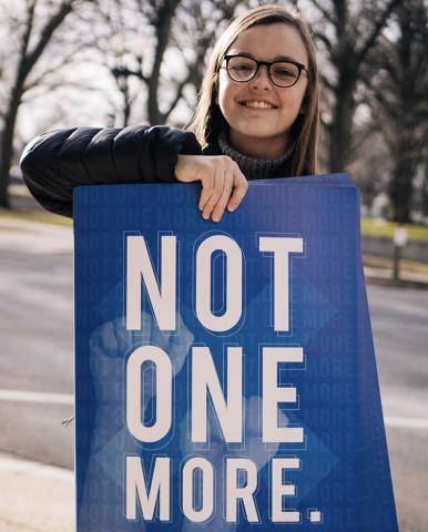 Natalie Dettmer with her winning poster design, "Not One More." Photo by Adobe Project 1324.