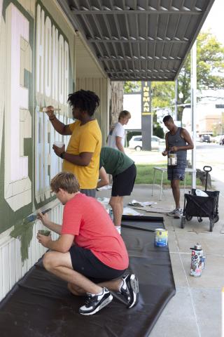 Students from Associate Professor of Art Sandra Williams’ University Honors seminar Graffiti Revolution help Shawn Dunwoody (right) paint his mural at the Veterans of Foreign Wars at 2431 N. 48th St. Photo by Eddy Aldana.