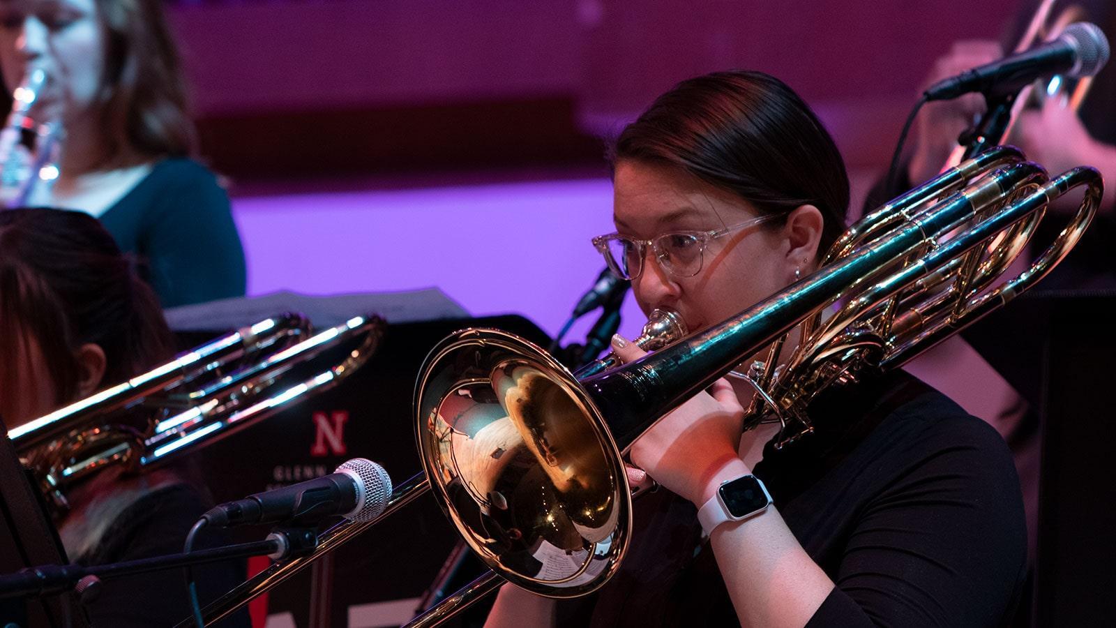 Close up of a trombone player on stage performing among fellow School of Music students.