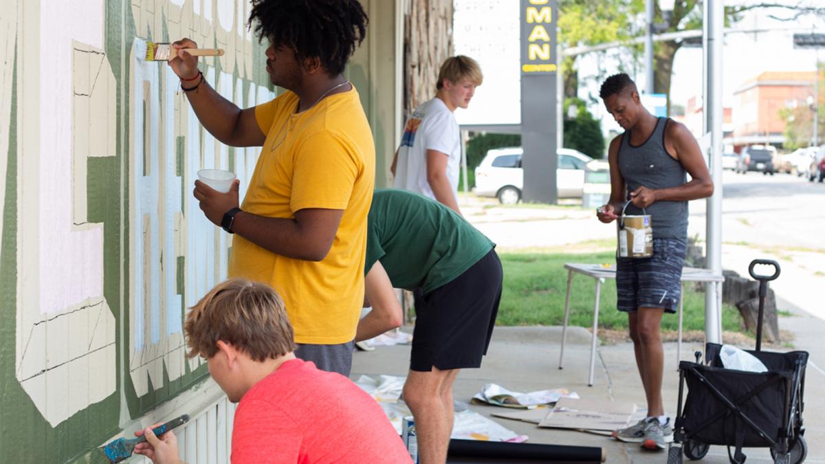 School of Art students outdoors painting a mural in the University Place neighborhood.