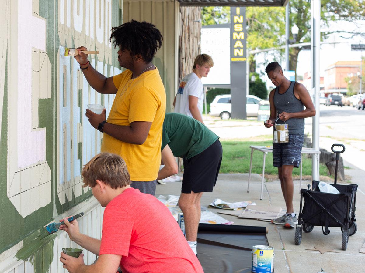 School of Art students outdoors painting a mural in the University Place neighborhood.