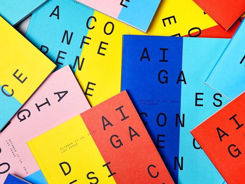 A pile of brightly colored AIGA Design Conference booklets.
