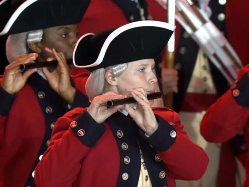 Alum Staff Sergeant Katie Rice Rogers in full regalia holding a flute during a performance among other performers.