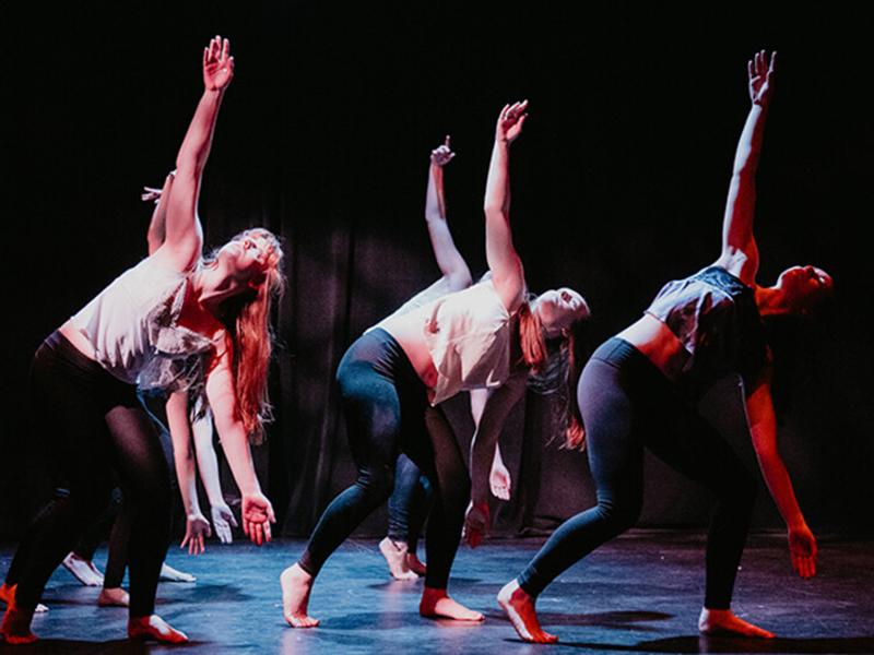Six Nebraska dance students on stage performing a piece choreographed by students, all in the same pose.