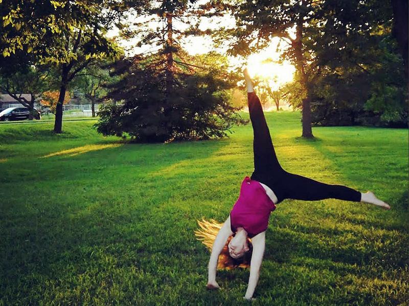 Nebraska Voice and Movement member cartwheeling in a campus green-space.