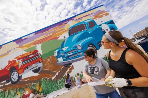 Sandra Williams, center, and Maddie Vanderbur, a senior in graphic design and the mural’s designer, look over a printout of the mural. Photo by Craig Chandler, University Communication and Marketing.