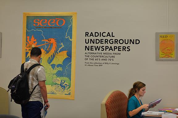 Students browse the underground newspapers exhibition in Love Library. Photo by Michael Reinmiller.